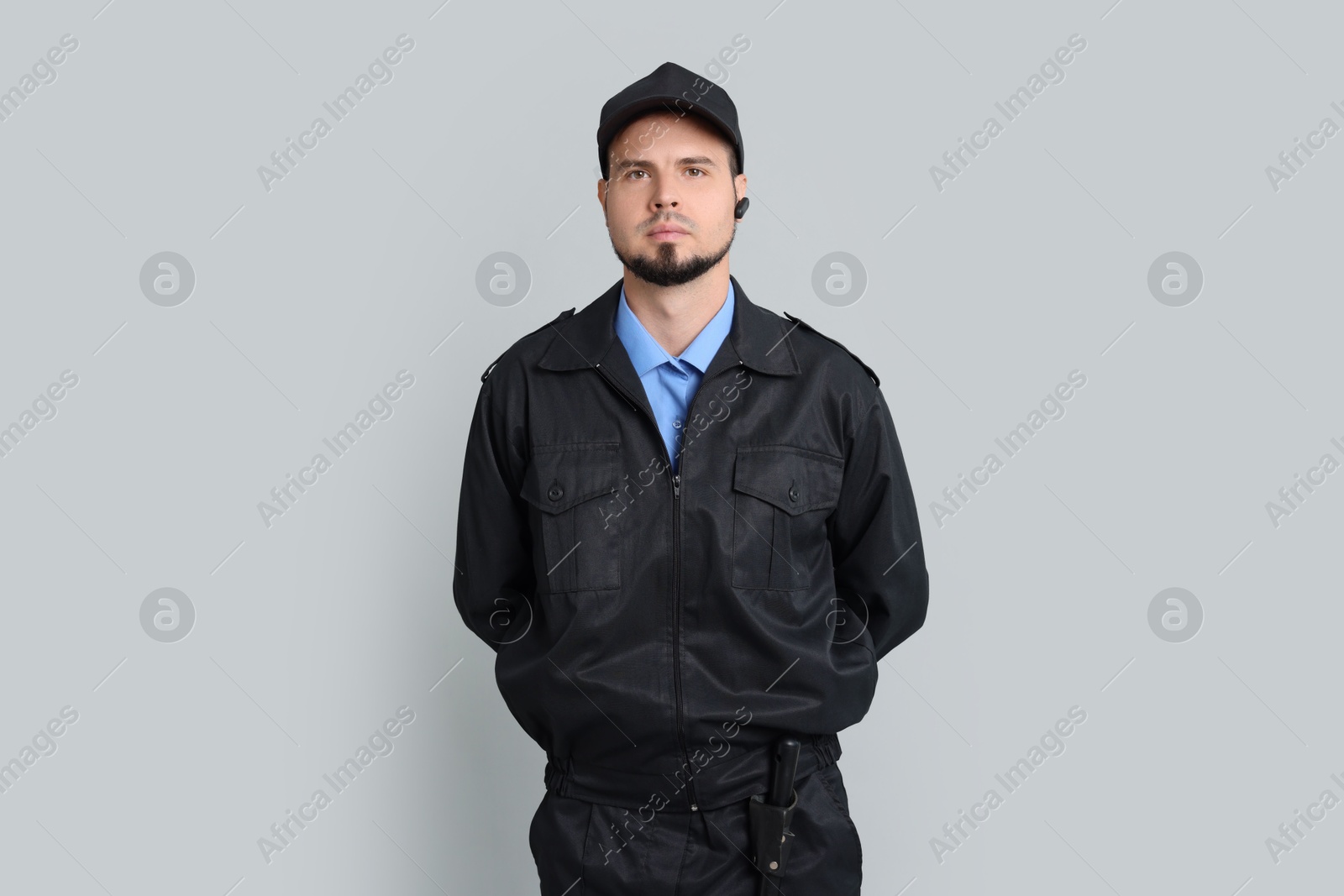 Photo of Security guard in uniform with earpiece on grey background