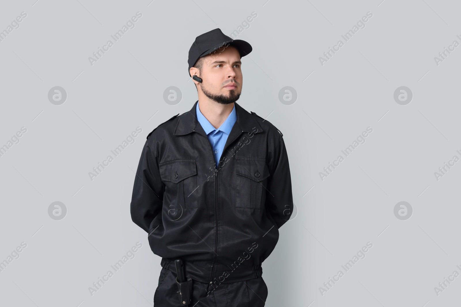 Photo of Security guard in uniform with earpiece on grey background