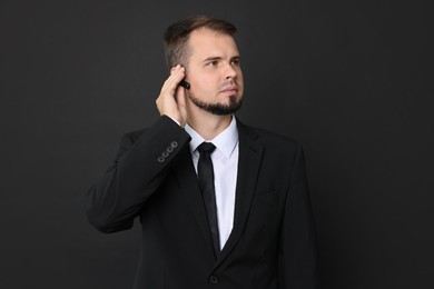 Photo of Young bodyguard in suit with earpiece on black background