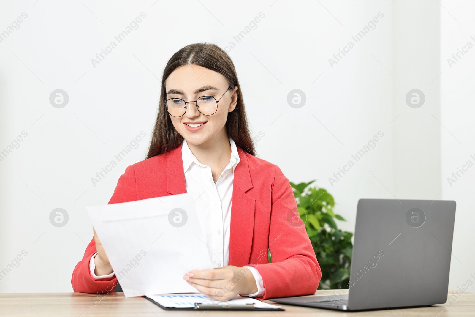 Photo of Budget planning. Young woman with papers and laptop at wooden table in office