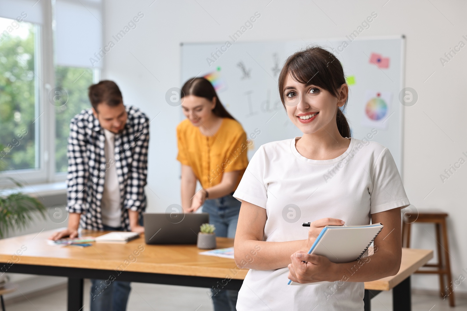 Photo of Happy young designer with notebook in office