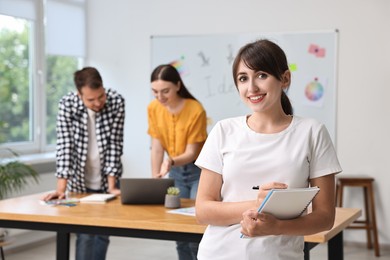 Happy young designer with notebook in office