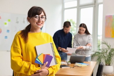 Portrait of happy young designer with notebook in office