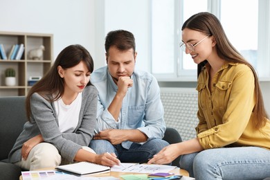 Designer discussing project with clients at table in office