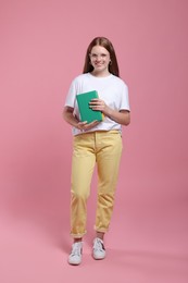 Teenage girl with books on pink background