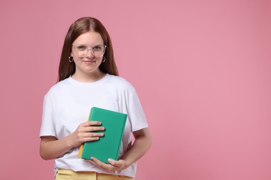 Photo of Teenage girl with books on pink background, space for text