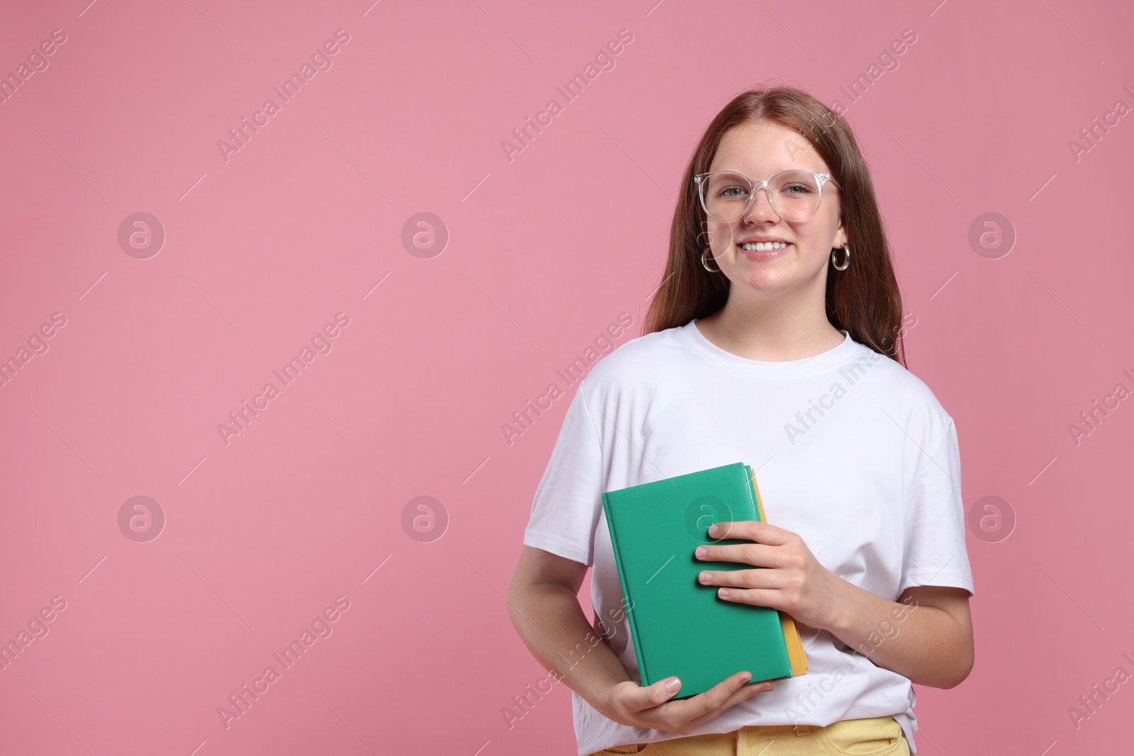 Photo of Teenage girl with books on pink background, space for text