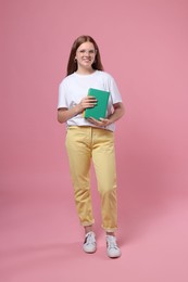 Teenage girl with books on pink background