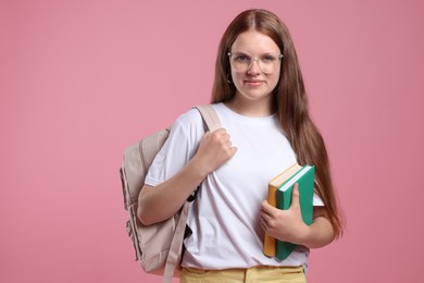 Photo of Teenage girl with backpack and books on pink background