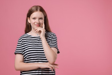 Portrait of teenage girl on pink background, space for text