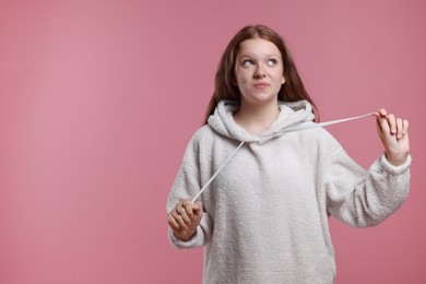 Portrait of teenage girl on pink background, space for text