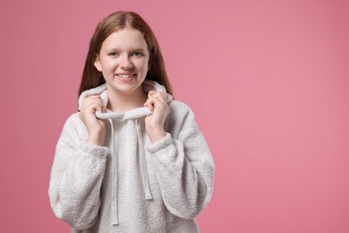 Portrait of teenage girl on pink background, space for text