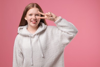 Photo of Teenage girl with showing v-sign on pink background