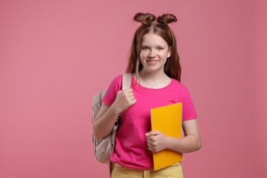 Photo of Teenage girl with backpack and notebook on pink background