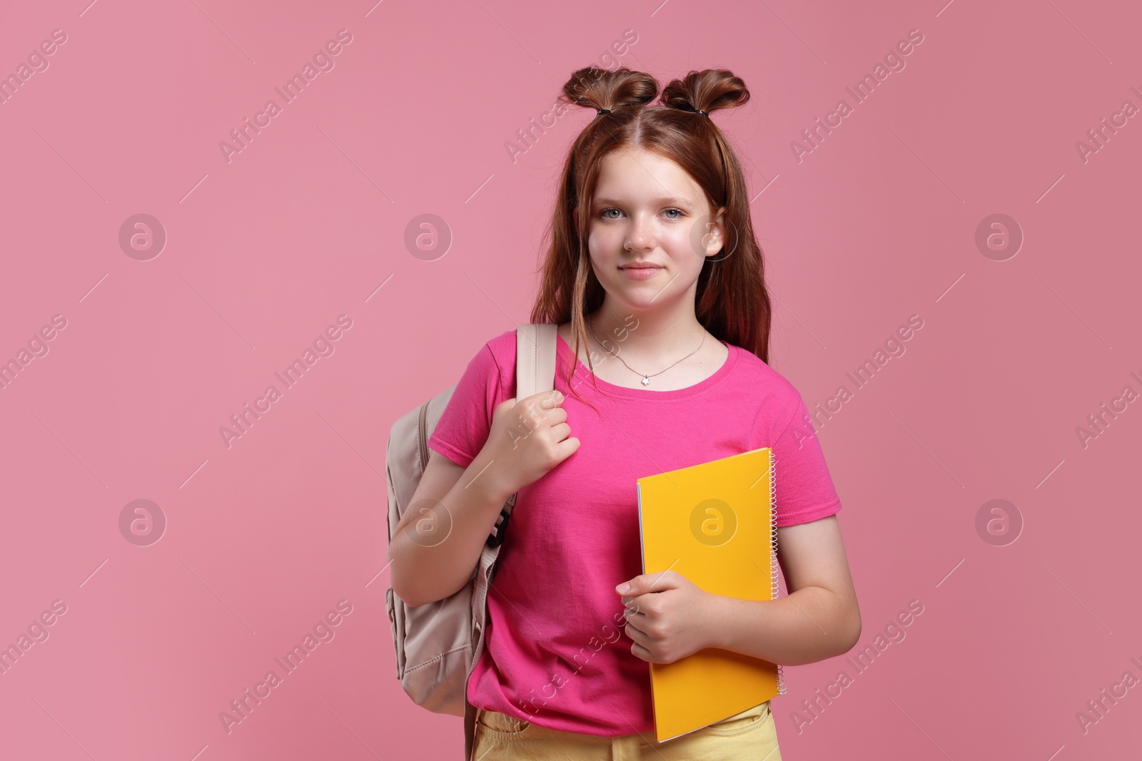 Photo of Teenage girl with backpack and notebook on pink background