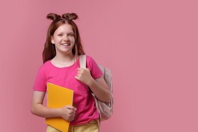 Teenage girl with backpack and notebook on pink background, space for text