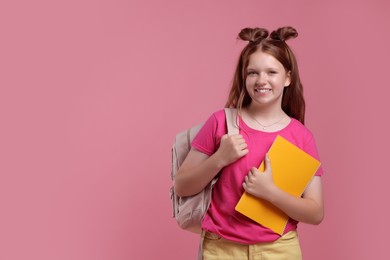 Teenage girl with backpack and notebook on pink background, space for text