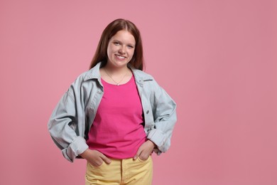 Portrait of teenage girl on pink background, space for text