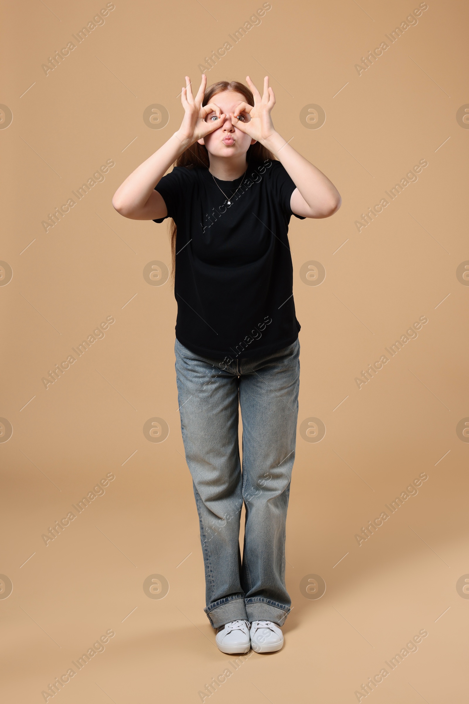 Photo of Cheerful teenage girl posing on beige background