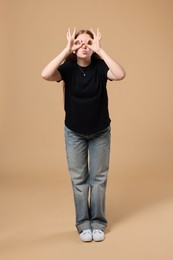 Cheerful teenage girl posing on beige background