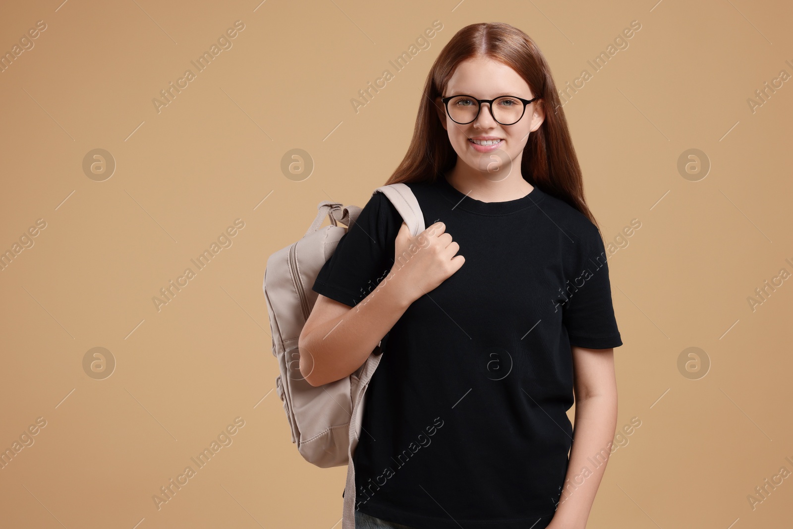 Photo of Teenage girl with backpack on beige background, space for text