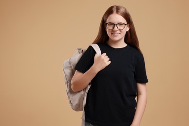 Teenage girl with backpack on beige background, space for text