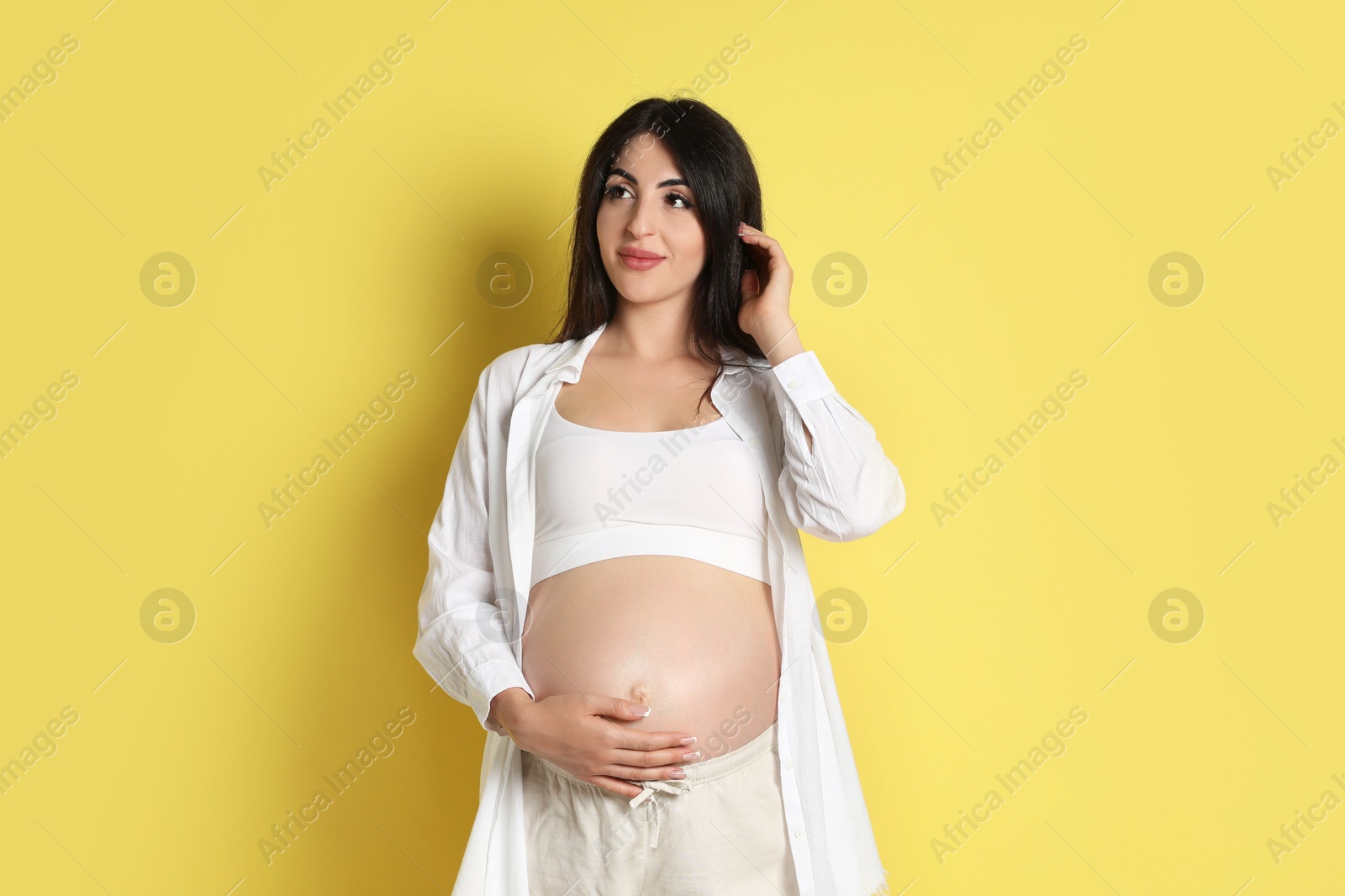 Photo of Portrait of beautiful pregnant woman on yellow background