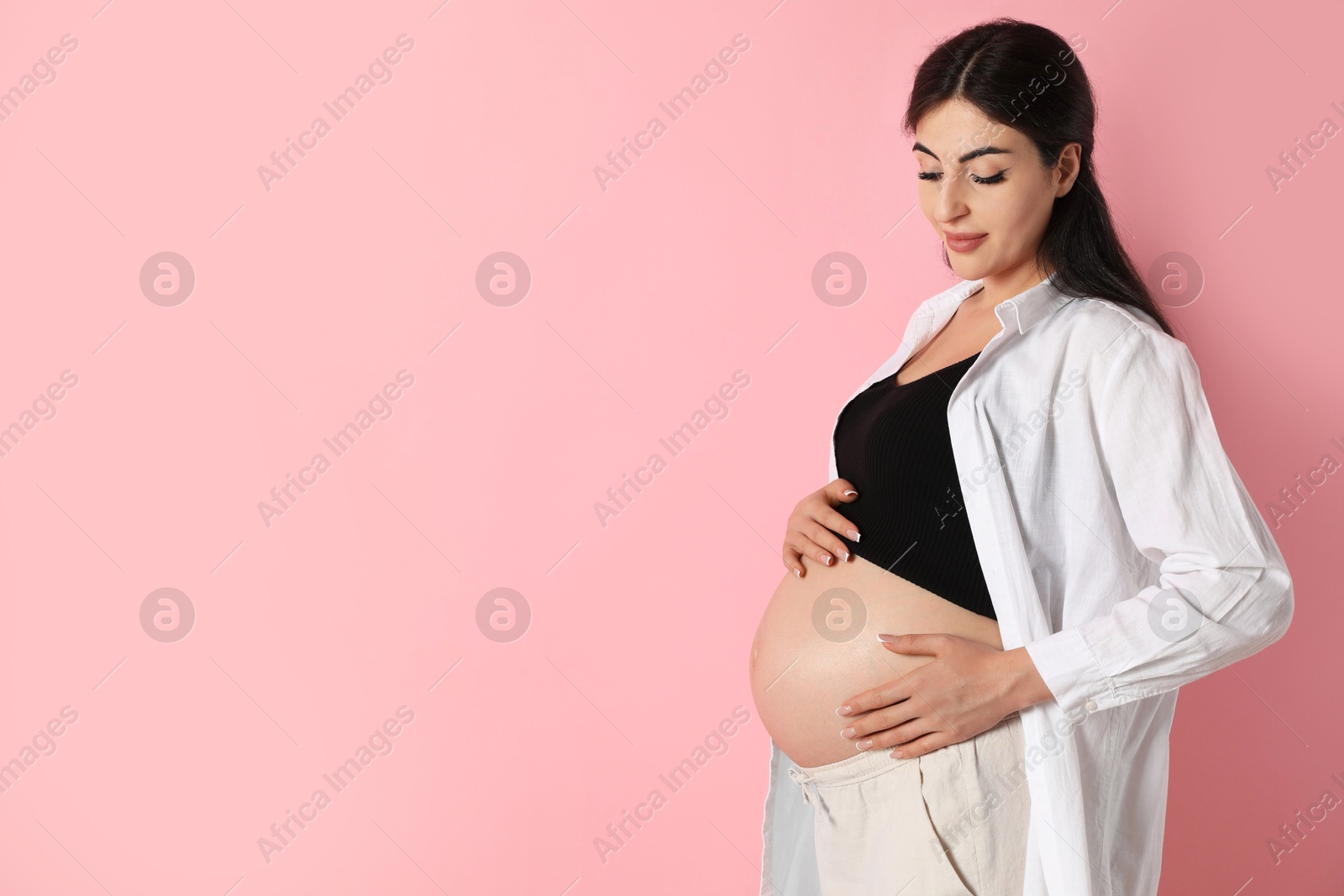 Photo of Portrait of beautiful pregnant woman on pink background, space for text