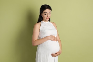 Portrait of beautiful pregnant woman on light olive background