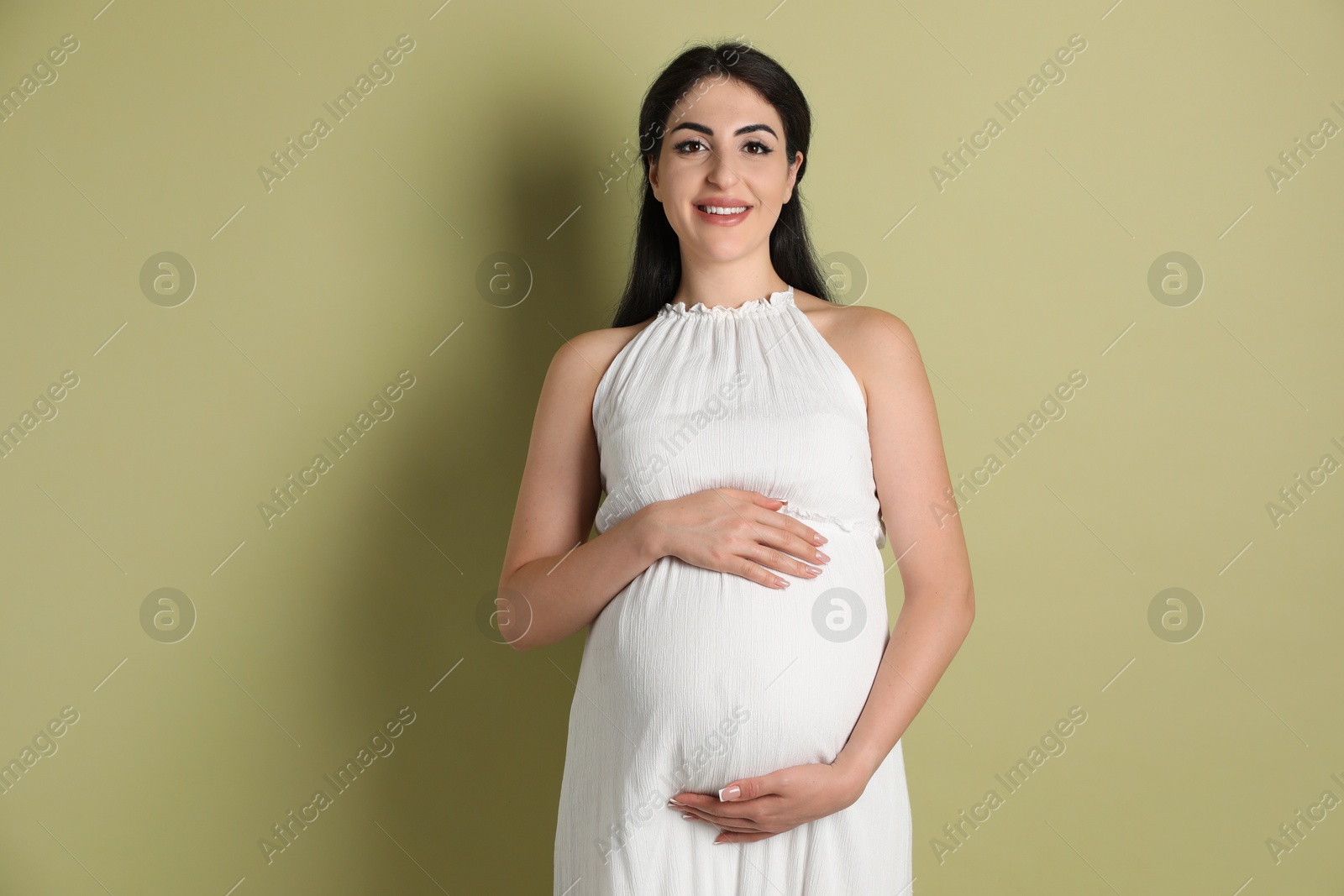 Photo of Portrait of beautiful pregnant woman on light olive background