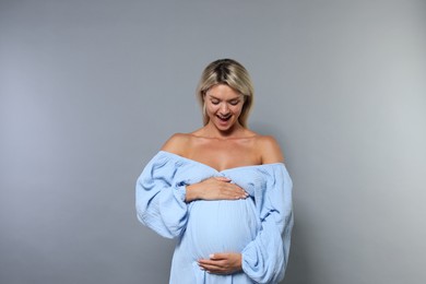 Portrait of beautiful pregnant woman on grey background