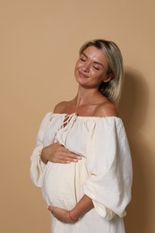 Portrait of beautiful pregnant woman on beige background