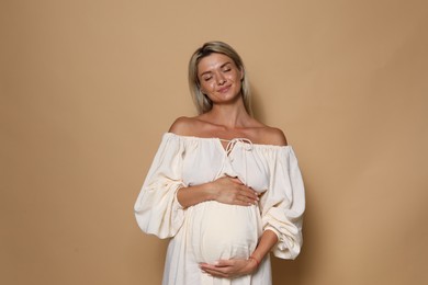 Portrait of beautiful pregnant woman on beige background