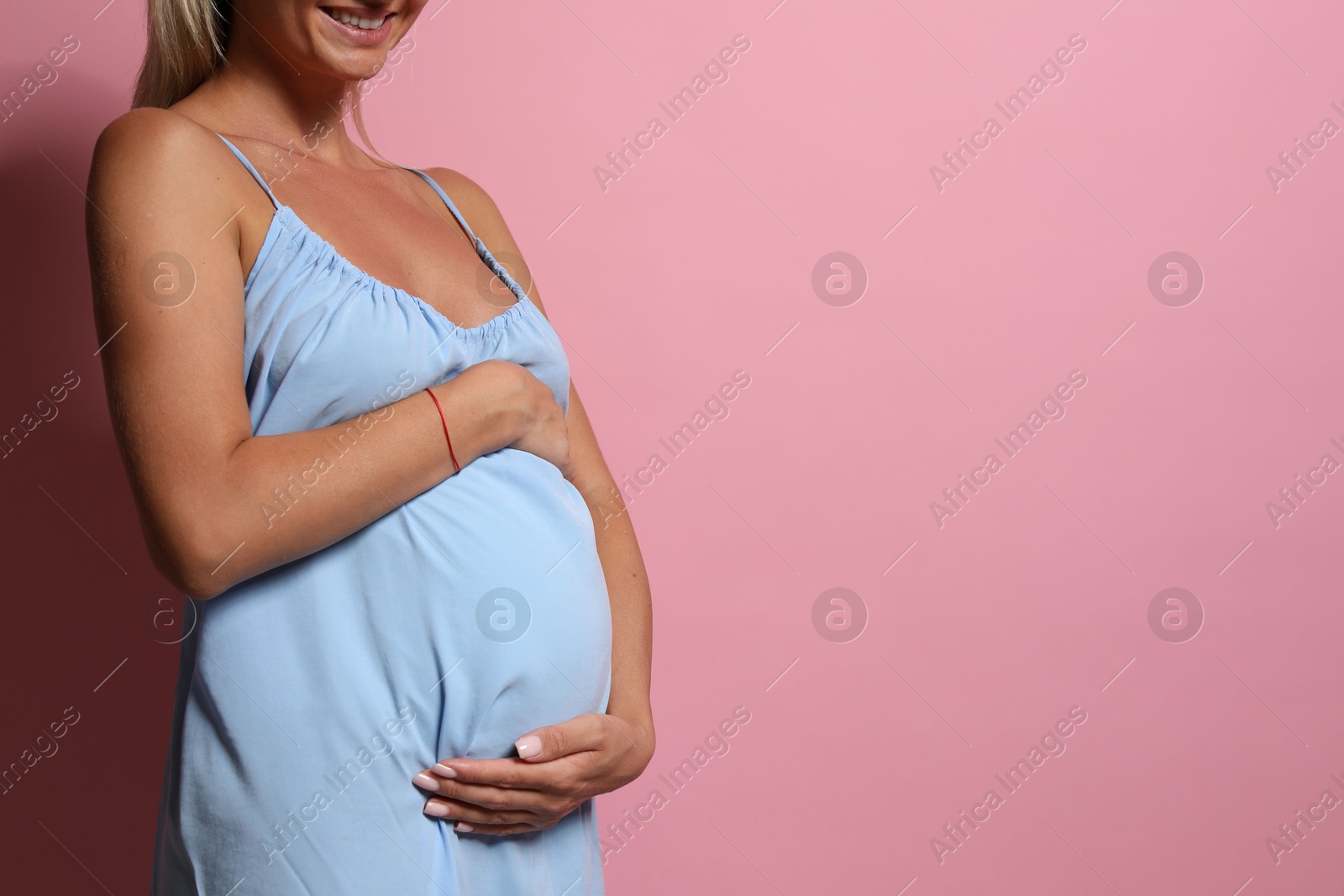 Photo of Pregnant woman on pink background, closeup. Space for text