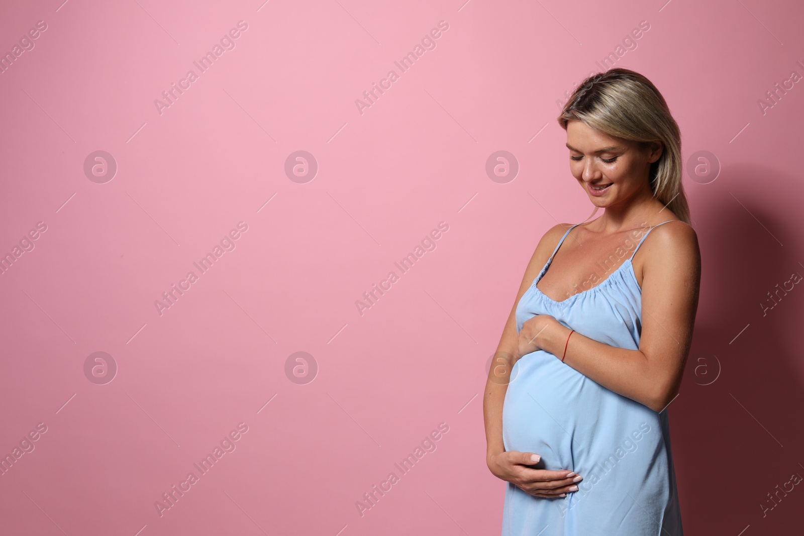 Photo of Portrait of beautiful pregnant woman on pink background, space for text