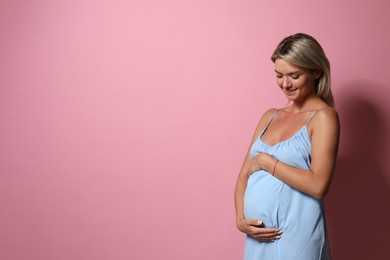 Portrait of beautiful pregnant woman on pink background, space for text