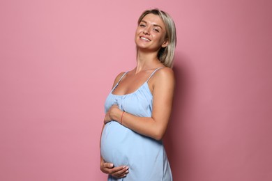 Portrait of beautiful pregnant woman on pink background