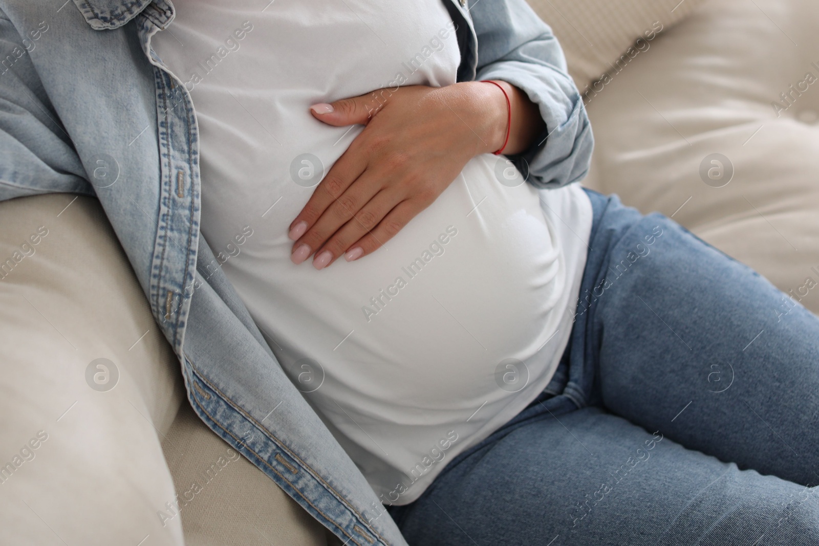 Photo of Pregnant woman on sofa at home, closeup