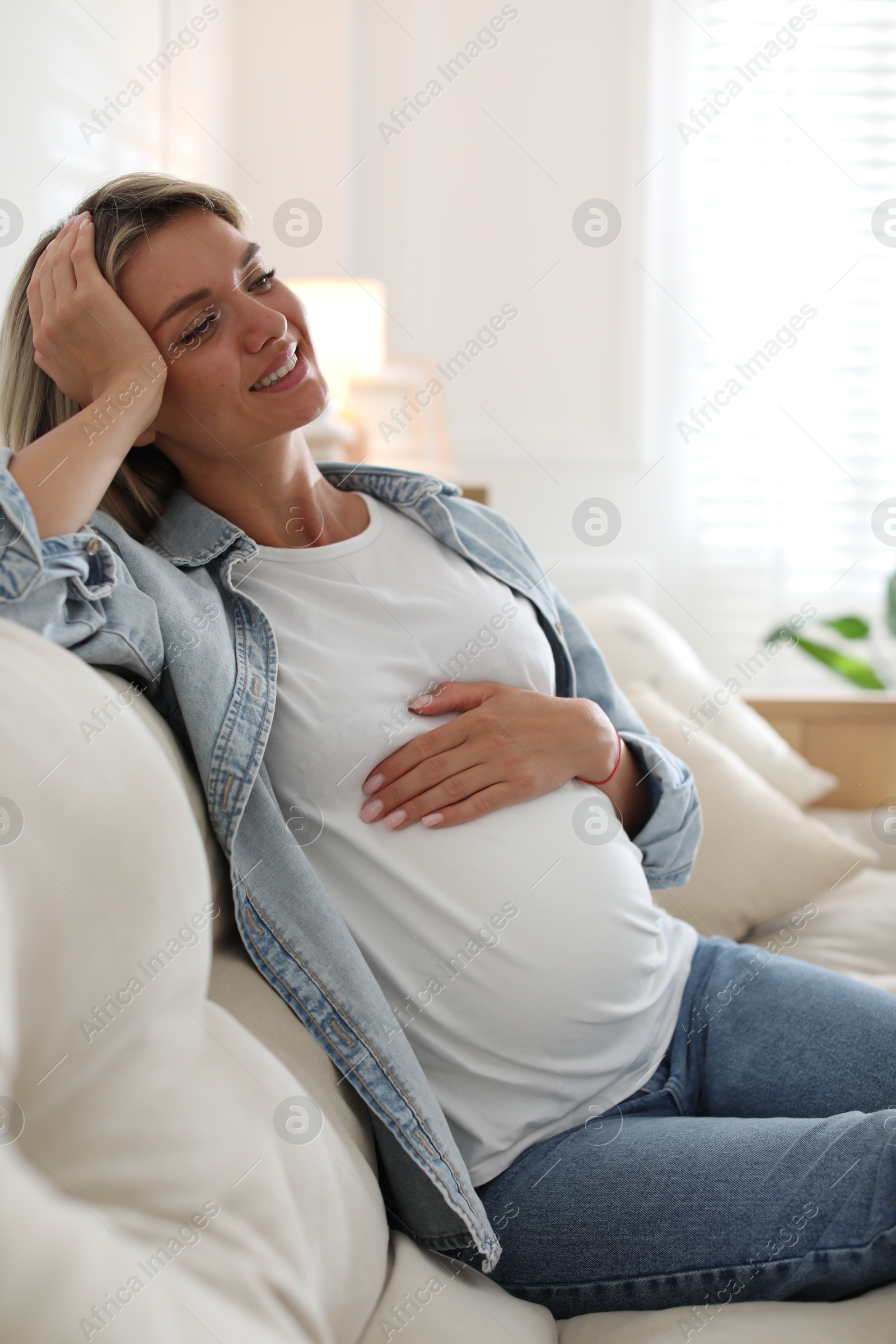 Photo of Portrait of beautiful pregnant woman on sofa at home