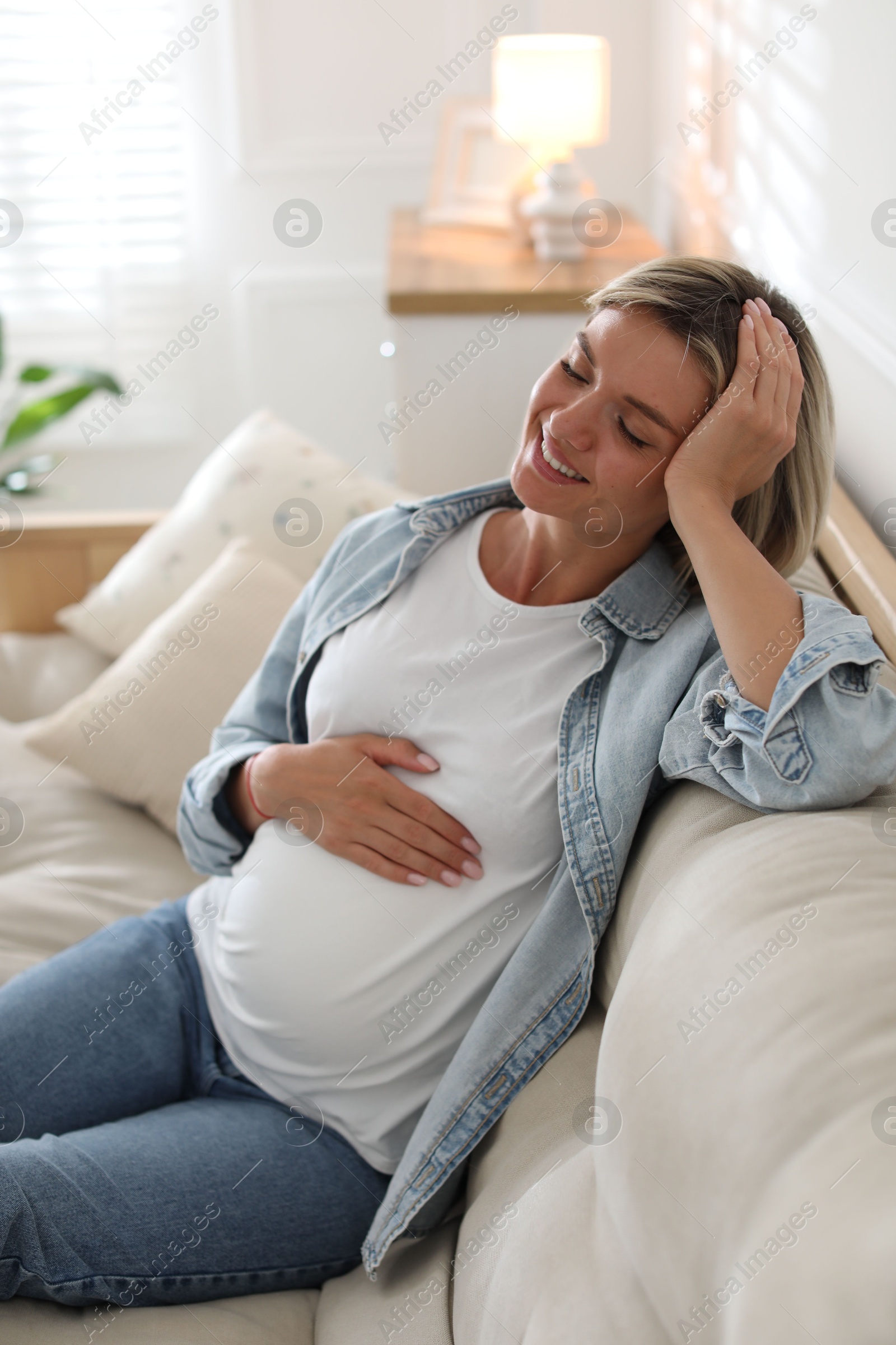 Photo of Portrait of beautiful pregnant woman on sofa at home