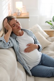 Portrait of beautiful pregnant woman on sofa at home