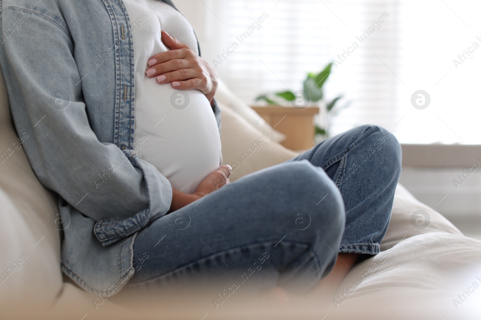 Photo of Pregnant woman on sofa at home, closeup