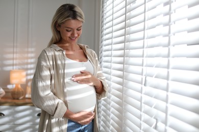 Portrait of beautiful pregnant woman near window at home