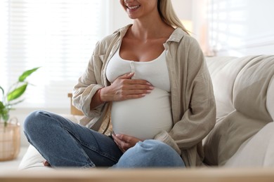 Photo of Pregnant woman on sofa at home, closeup