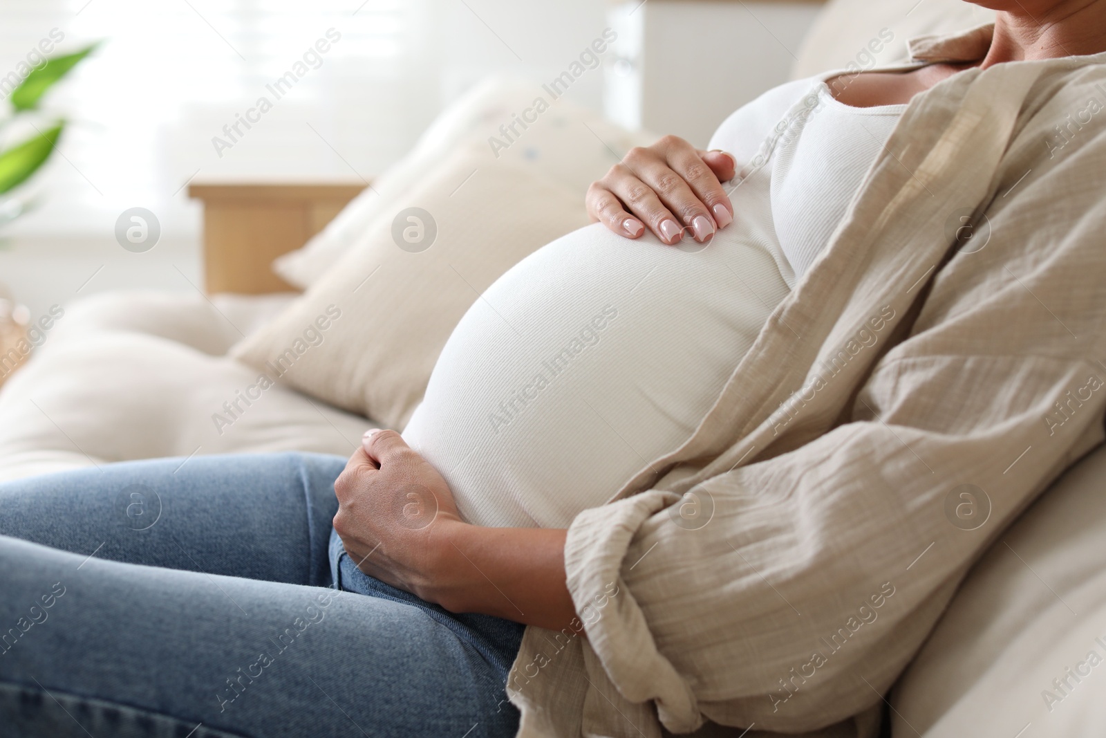 Photo of Pregnant woman on sofa at home, closeup