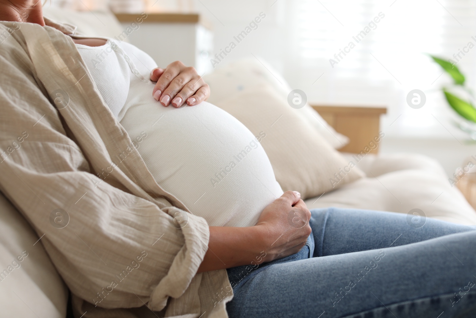 Photo of Pregnant woman on sofa at home, closeup