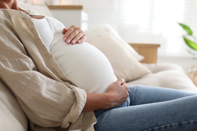 Photo of Pregnant woman on sofa at home, closeup