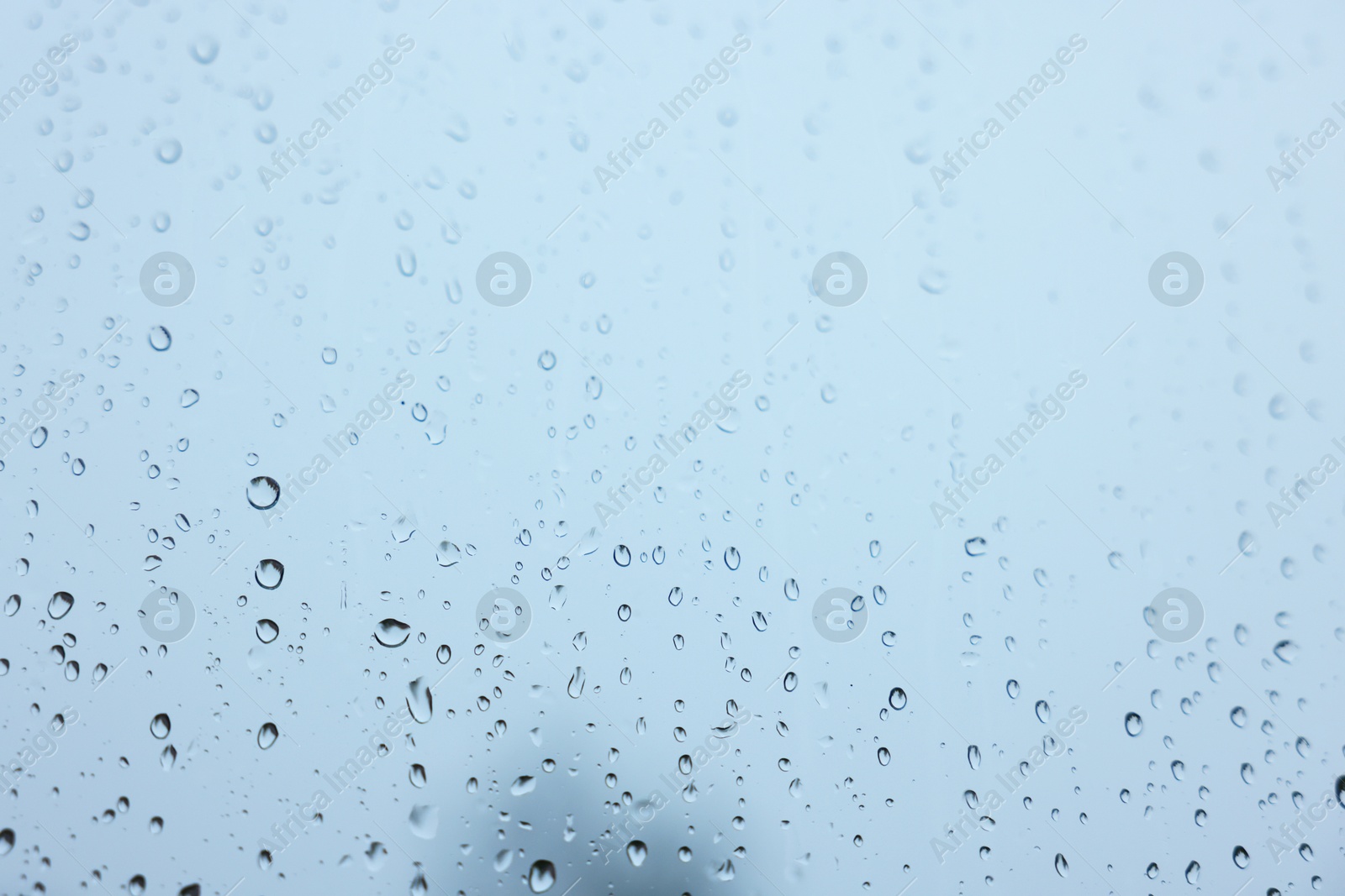 Photo of View on sky through window with water droplets on rainy day, closeup