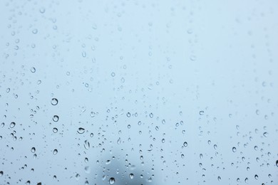 View on sky through window with water droplets on rainy day, closeup