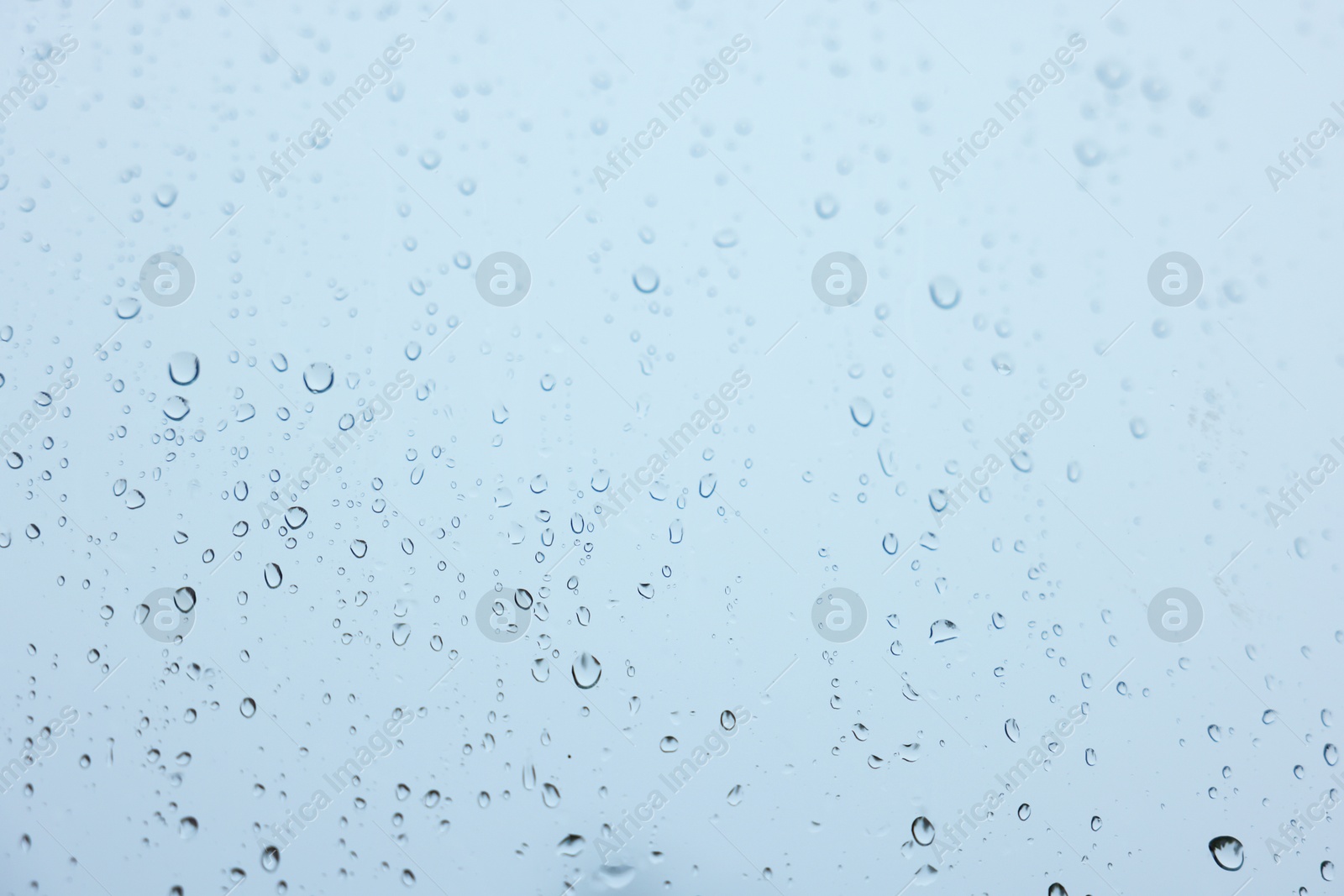 Photo of View on sky through window with water droplets on rainy day, closeup